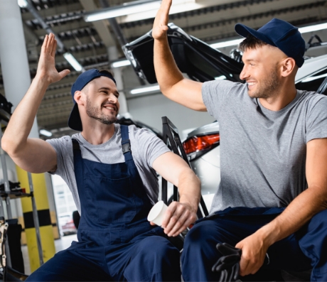Two auto mechanics about to high five